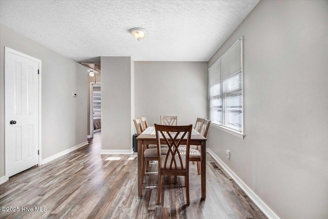 dining area featuring a textured ceiling and wood-type flooring