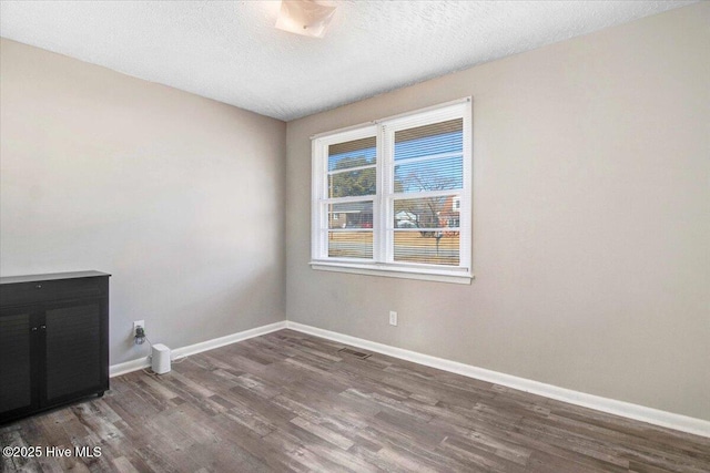 empty room with a textured ceiling and dark wood-type flooring