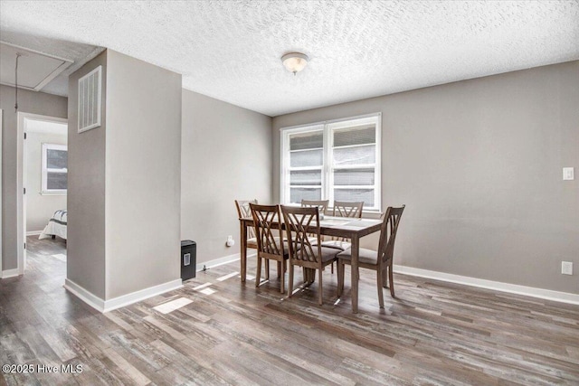 dining room featuring a textured ceiling and dark hardwood / wood-style flooring