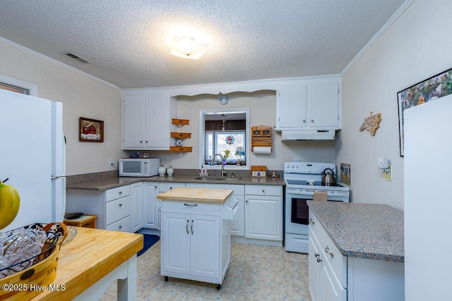 kitchen featuring visible vents, a sink, wood counters, a center island, and white appliances