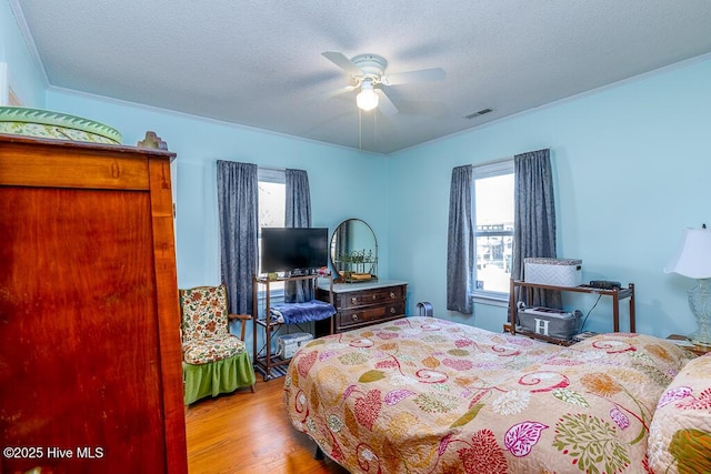 bedroom featuring visible vents, multiple windows, a textured ceiling, and wood finished floors