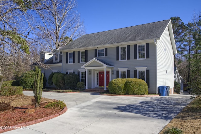 colonial home with a shingled roof and driveway