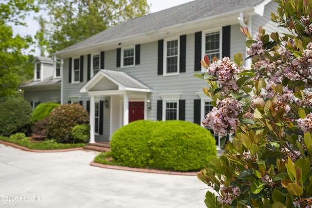 colonial-style house featuring roof with shingles