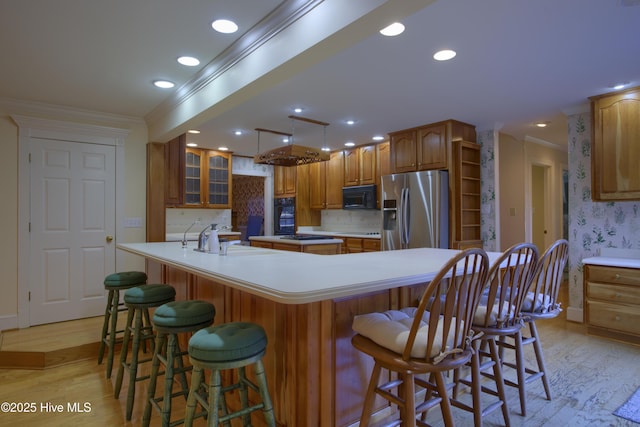 kitchen with light hardwood / wood-style floors, backsplash, black appliances, and a kitchen bar