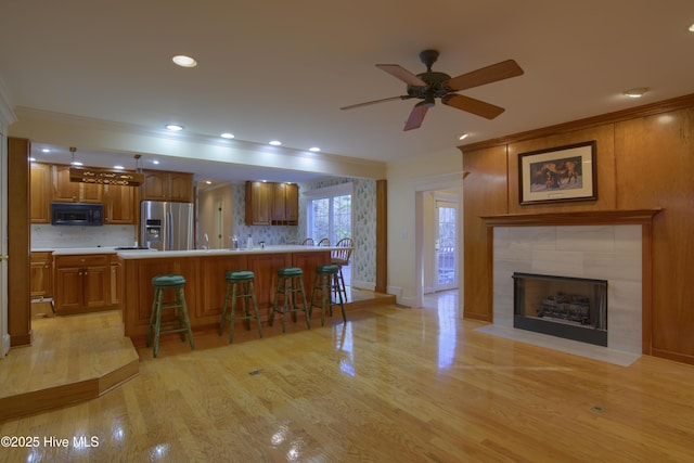 kitchen with brown cabinets, black microwave, stainless steel fridge, and crown molding
