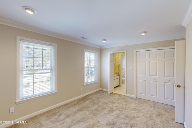 unfurnished bedroom featuring light colored carpet, connected bathroom, and multiple windows