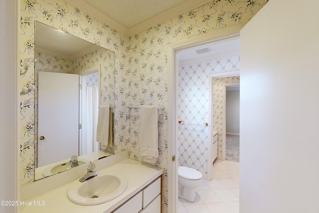 bathroom with vanity, wallpapered walls, tile patterned flooring, crown molding, and toilet