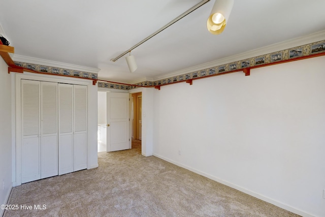 unfurnished bedroom with carpet floors, a closet, ornamental molding, and rail lighting