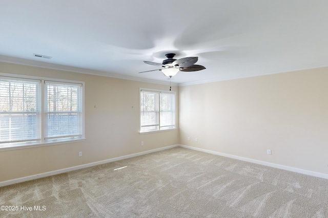 spare room with light carpet, ceiling fan, baseboards, and ornamental molding