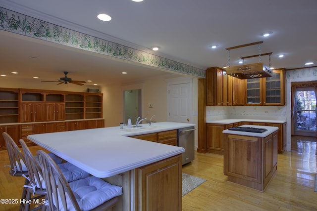 kitchen with dishwasher, a large island with sink, sink, light hardwood / wood-style flooring, and a kitchen breakfast bar