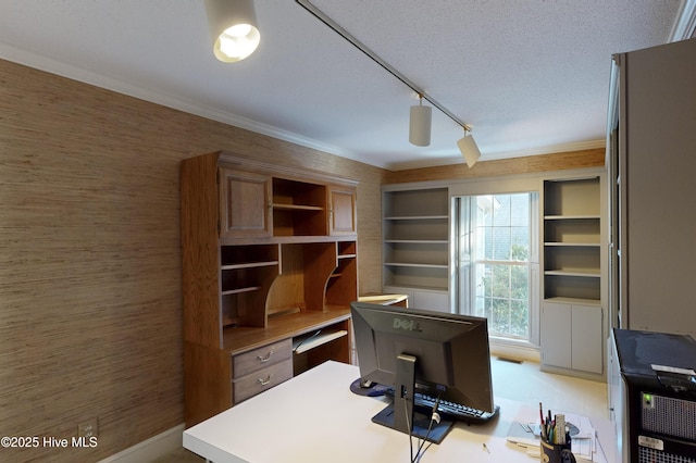 home office featuring a textured ceiling, crown molding, track lighting, and built in desk