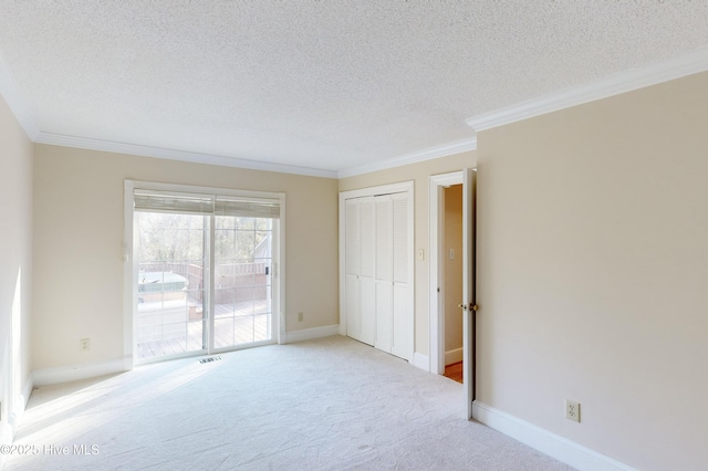 unfurnished bedroom featuring a textured ceiling, a closet, ornamental molding, access to exterior, and carpet flooring