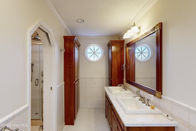 bathroom with tile patterned flooring, tile walls, a textured ceiling, ornamental molding, and vanity