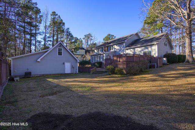 rear view of house with a deck, cooling unit, and a lawn