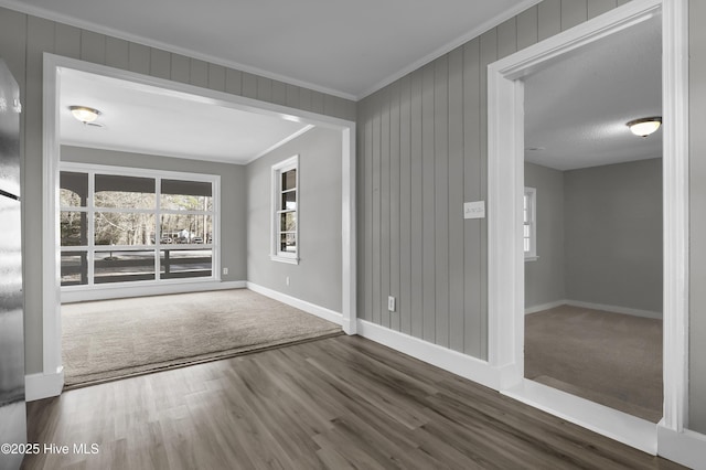 empty room featuring crown molding, wood-type flooring, and wooden walls