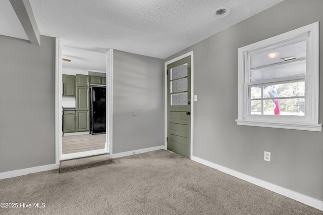 spare room featuring a textured ceiling and carpet flooring