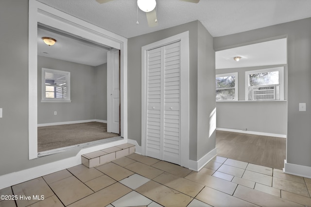 corridor with a textured ceiling and light tile patterned floors