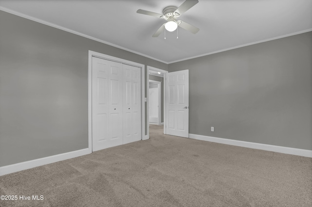 unfurnished bedroom featuring ceiling fan, a closet, crown molding, and carpet flooring