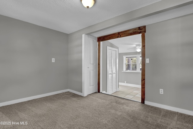 empty room featuring a textured ceiling, ceiling fan, and light colored carpet