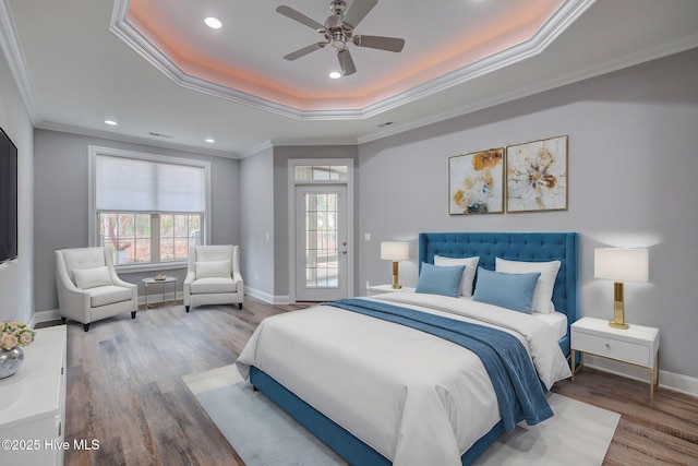 bedroom with ceiling fan, a tray ceiling, multiple windows, and ornamental molding