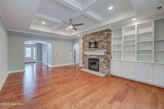 unfurnished living room featuring beamed ceiling, a stone fireplace, light hardwood / wood-style floors, ornamental molding, and coffered ceiling