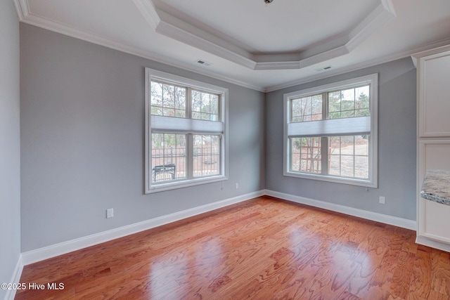 unfurnished room with a tray ceiling, light hardwood / wood-style flooring, and ornamental molding