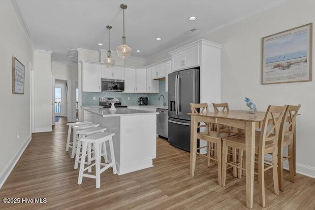 1788 New River Inlet Rd, North Topsail Beach, NC 28460 - kitchen featuring stainless steel appliances, ornamental molding, a kitchen island, white cabinets, and light countertops