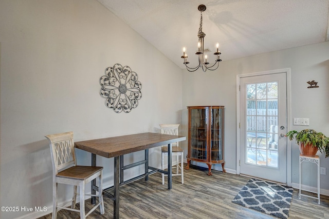 dining space with a textured ceiling, a chandelier, lofted ceiling, and hardwood / wood-style flooring