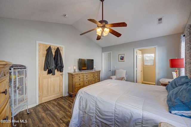 bedroom with a textured ceiling, dark wood-type flooring, a closet, vaulted ceiling, and ceiling fan