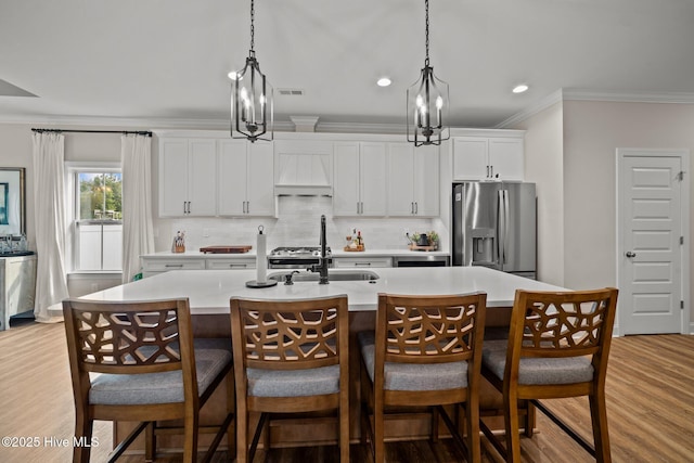 kitchen with backsplash, a notable chandelier, a kitchen island with sink, and stainless steel fridge with ice dispenser