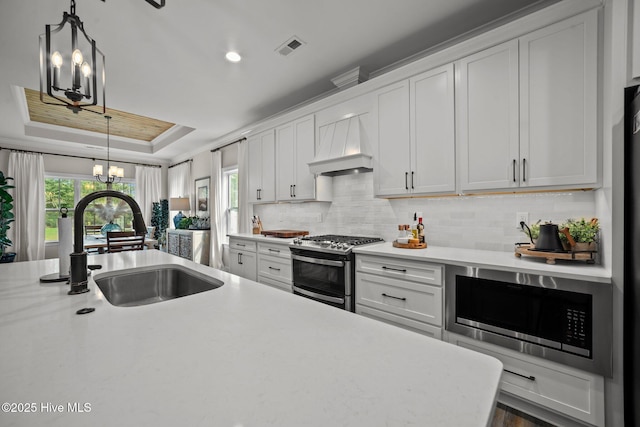 kitchen featuring appliances with stainless steel finishes, white cabinetry, and premium range hood