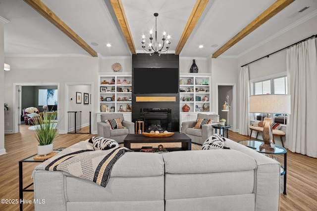 living room featuring a notable chandelier, built in shelves, light wood-type flooring, a fireplace, and beamed ceiling