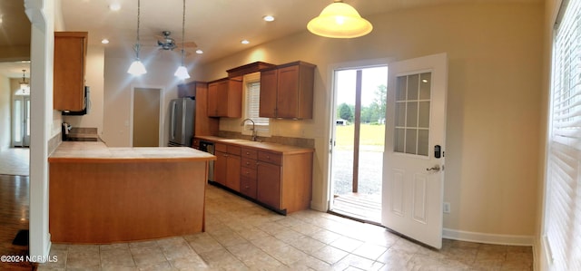 kitchen with sink, decorative light fixtures, tile countertops, ceiling fan, and stainless steel fridge