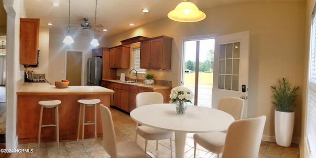 kitchen featuring stainless steel refrigerator, light tile patterned floors, pendant lighting, and sink