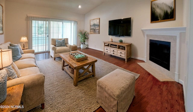 living room featuring lofted ceiling, dark hardwood / wood-style flooring, and a tiled fireplace