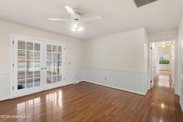 empty room featuring ceiling fan, french doors, and hardwood / wood-style floors