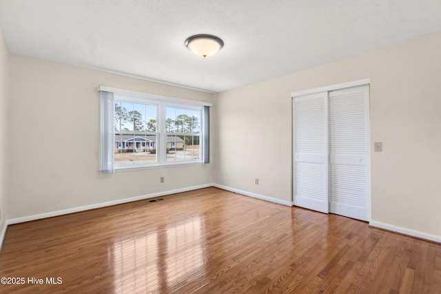 unfurnished bedroom featuring hardwood / wood-style flooring, a textured ceiling, and a closet