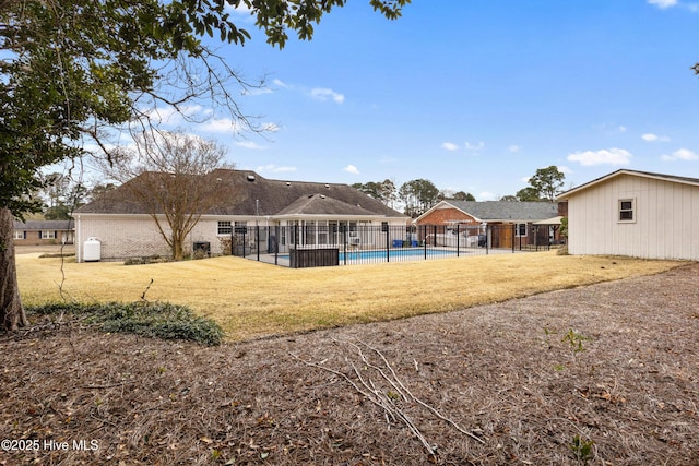 back of house with a yard and a fenced in pool