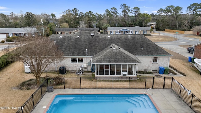 back of property with a sunroom and a fenced in pool