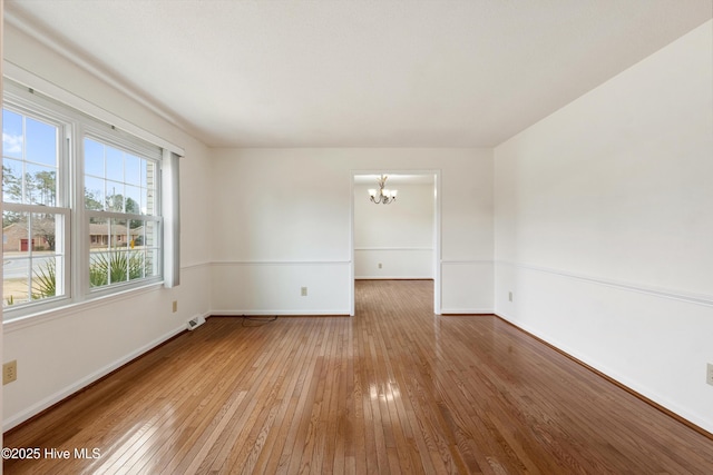 spare room featuring a chandelier and hardwood / wood-style floors