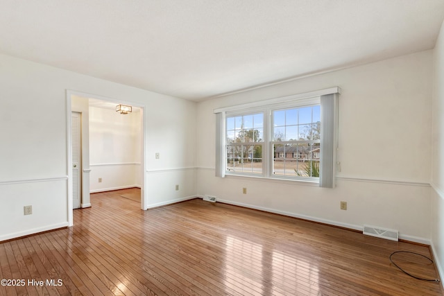 unfurnished room featuring an inviting chandelier and hardwood / wood-style floors