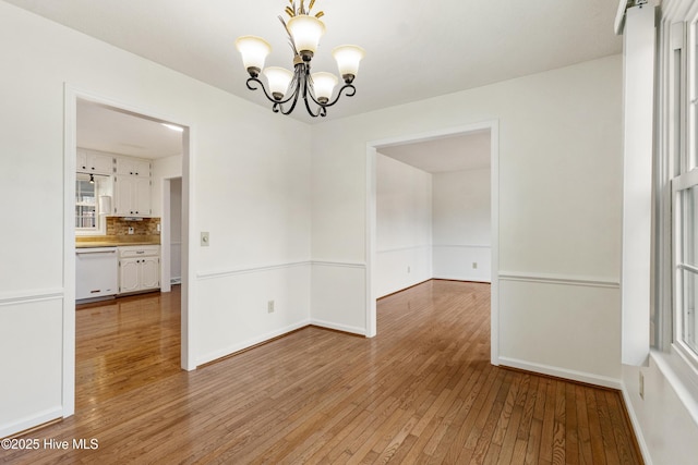 unfurnished dining area featuring light hardwood / wood-style flooring and an inviting chandelier