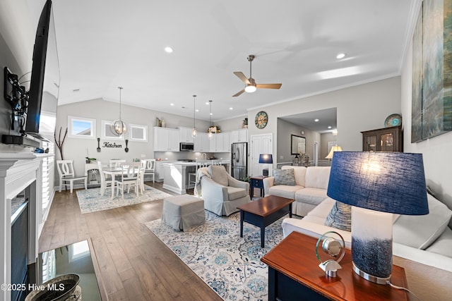 living room with ceiling fan, dark wood-type flooring, lofted ceiling, and crown molding