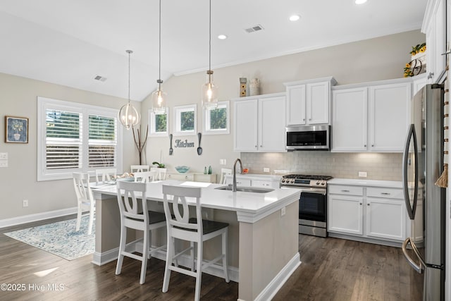 kitchen featuring sink, hanging light fixtures, stainless steel appliances, and an island with sink