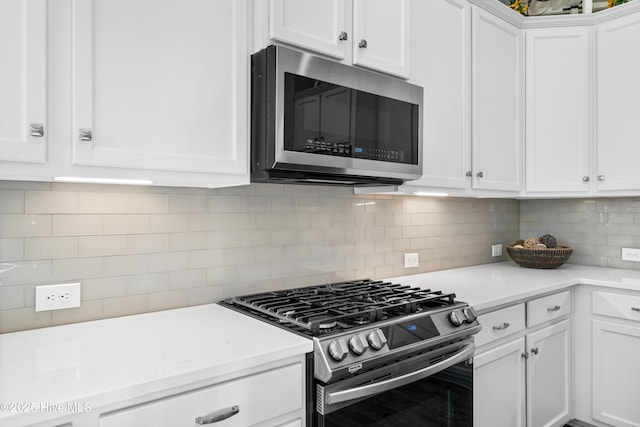 kitchen with backsplash, appliances with stainless steel finishes, and white cabinetry