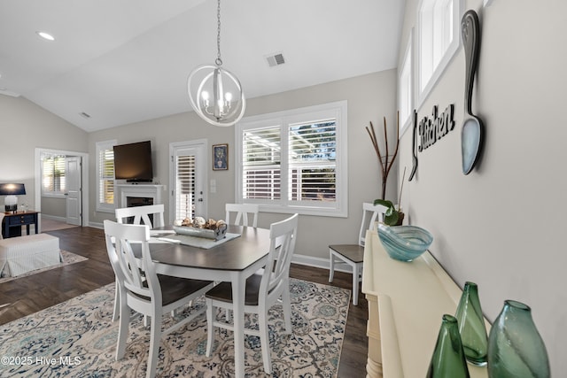 dining room featuring dark hardwood / wood-style floors, lofted ceiling, and a notable chandelier