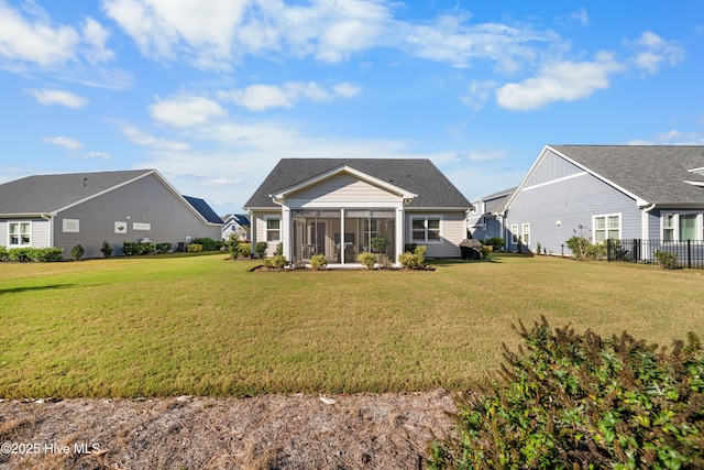 rear view of property with a sunroom and a yard