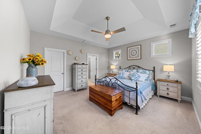 carpeted bedroom featuring ceiling fan and a tray ceiling