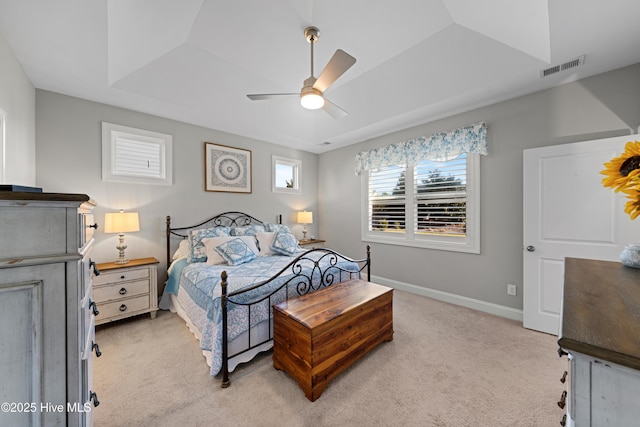 bedroom featuring ceiling fan, light colored carpet, and a tray ceiling