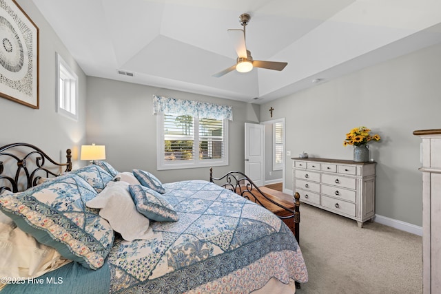 carpeted bedroom with ceiling fan and a tray ceiling